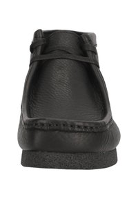 Svart lädersko med slät yta, låg profil, rund tå och snörning. Har en gummisula för bra grepp.