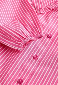 Ružičasta prugasta pamučna košulja s tankim bijelim prugama, nabrani rubovi rukava, ovratnik s naborima i ružičasti gumbi.