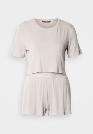 Beige two-piece set featuring a cropped short-sleeve top and matching shorts. The fabric has a ribbed texture and elastic waistband.