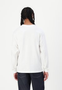 Langermet hvit bomull T-skjorte med rund hals og en glatt tekstur, sammen med blå denimjeans.