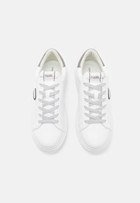 Vita sneakers med en slät läderyta, rund tå, grå detaljer och platta snörningar. En cirkulär logotypdetalj på sidan.