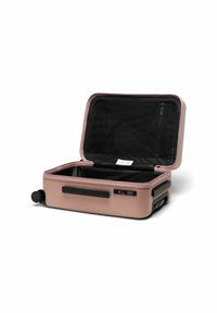 Valise rigide en rose doré, avec un intérieur noir, une poche zippée, des roues doubles et un verrou à combinaison. Ouverte, montrant l'espace de rangement.