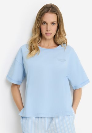 Light blue short-sleeve top with a relaxed fit, featuring a crew neckline and small text logo on the chest. Soft fabric with smooth texture.