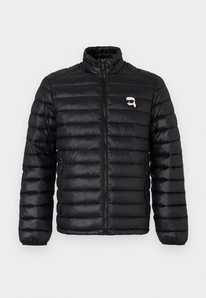 Must have ülikerge must puffer jakk, millel on kõrge krae, horisontaalne tikand ja rinna logo. Valmistatud läikivast materjalist, mis on varustatud painduva sõrmedega ja tõmbluku sulgemisega.
