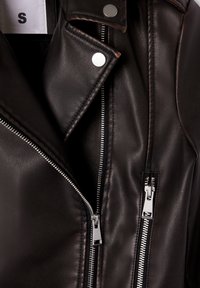 Czarna skórzana kurtka z srebrnymi zamkami błyskawicznymi i napami, rozmiar mały, widoczna na białej metce wewnętrznej.