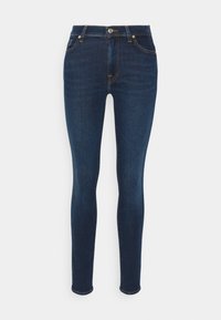 Jeans ajustados de mezclilla azul oscura con una textura suave, que cuentan con un cierre frontal de botón, cinco bolsillos y costuras en contraste de color naranja.
