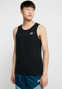 Crna Nike majica bez rukava od pamuka. Ima okrugli izrez, dizajn bez rukava i mali bijeli logotip na lijevoj strani prsnog dijela.