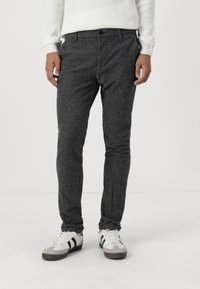 Pantalones grises texturizados con un ajuste slim, con cierre de botón y bolsillos, combinados con zapatillas deportivas blancas y grises.