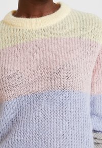 Gebreide trui met een zachte, lichte textuur. Heeft horizontale strepen in pastelkleuren van geel, roze en lavendel. Ronde halslijn.