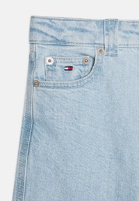 Șorturi din denim de un albastru deschis cu o textură fină, având cusături contrastante, accesorii din argint și un mic logo colorat pe buzunar.