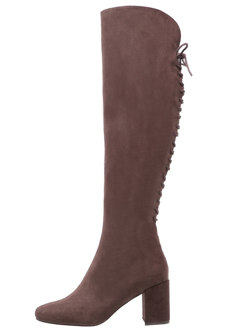 Botas de ante marrones hasta la rodilla con un tacón bloque y un detalle de lazada estilo corsé en la parte trasera. Textura suave y diseño aerodinámico.