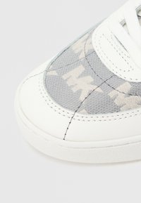 Λευκό αθλητικό παπούτσι με γκρι υφασμάτινο επάνω μέρος με σχέδιο, στρογγυλή μύτη και επίπεδη λαστιχένια σόλα. Διαθέτει αντίθετη ραφή και επίπεδα κορδόνια.