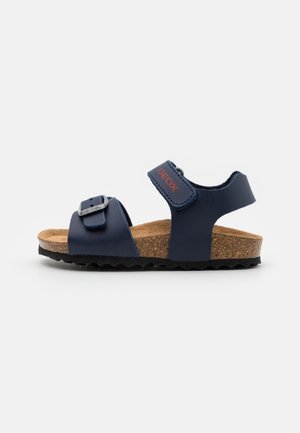 Børns mørkeblå sandal med justerbar spænde og velcroremme, korksål og sort tekstureret sål.