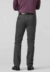 Grijze chino's met een slim fit, voor- en achterzakken, subtiele stiksels en een gladde stofstructuur. Een zwarte riem en schoenen complementeren de look.