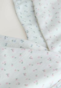 Țesătură albă cu un imprimeu floral mic în nuanțe de roz și albastru, având tulpini verzi. Textură moale cu un model delicat pe întreaga suprafață.