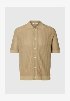 Beżowa koszulka polo z krótkim rękawem, dzianinowa, z zapięciem na guziki z przodu i teksturowanym, perforowanym wzorem tkaniny.