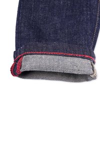 Tumma sininen farkkuhaalari, jonka lahkeissa on harmaavalkoinen raidoitettu vuori ja punaiset ompeluseparated lehden reunassa.