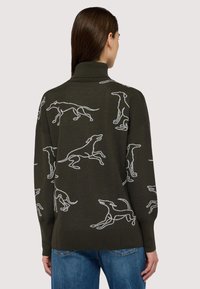 Mörkgrön tröja med vita hundgrafiker. Har en hög krage, ribbade muddarna och en lös passform. Materialet verkar mjukt och texturerat.