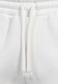 Vita bomullssweatpants med en texturerad midja, dragsnören och en sidoficka, med en slät tyg yta.