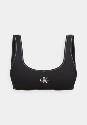 Melns crop tops ar platajām siksnām, baltu zigzagveida šuvju un baltu "CK" Calvin Klein logotipu priekšpusē centrā.