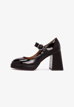 Chaussure Mary Jane en simili cuir noir avec un large talon bloc, un bout rond et une sangle ajustable avec un détail de boucle circulaire.