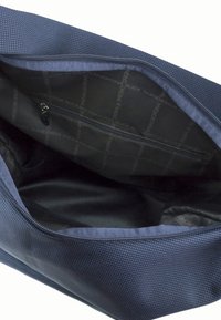 Tummansininen teksturoidulla sisäpuolella oleva laukku, jossa on vetoketjullinen tasku. Vuoritettu mustalla kankaalla, jossa on toistuva logokuosi. Sujuva pinta, tilava muotoilu.