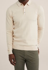 Light beige long-sleeve polo with a textured knit pattern, three-button placket, and ribbed cuffs and hem. It has a small logo detail.