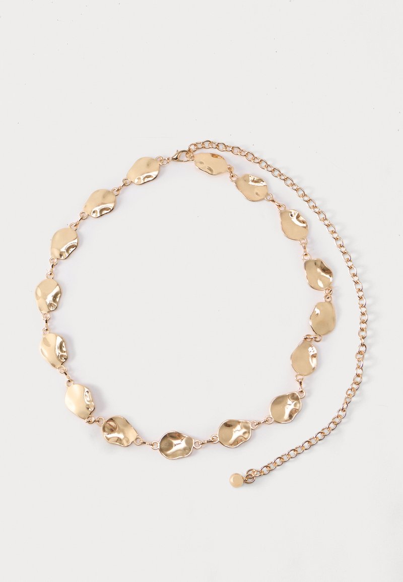 Ζώνη σε χρυσό τόνο με συνδεδεμένες παράτυπες οβάλ μεταλλικές πλάκες και ρυθμιζόμενο κούμπωμα αλυσίδας σε απλό φόντο.