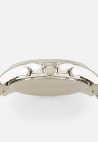 Silver stainless steel watch with a round case, smooth bezel, and three push buttons. The back is flat and unembellished.