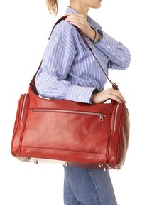Borsone in pelle rossa con cerniere argentate, base piatta e numerose tasche esterne. Ha una tracolla rimovibile.