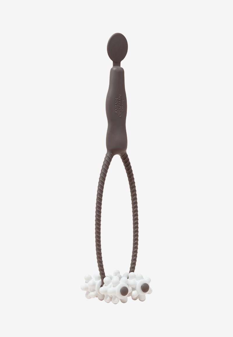 Brown silicone tool with a looped grip and a round top. White textured attachments resembling flowers with brown centers at the bottom.