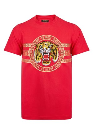 Czerwona koszulka z krótkim rękawem z dużą ryczącą głową tygrysa w okrągłym wzorze oraz tekstem "Ed Hardy" wokół niej.