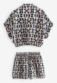 Kortärmad topp och shorts med elastisk midja i ljust rosa tyg, med ett svart blommönster. Mjuk textur och avslappnad passform.
