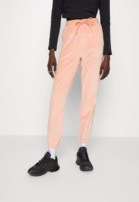 Persikofärgade, löst sittande sweatpants med elastiska muddar och midja, med sidofickor och en texturerad tyg.