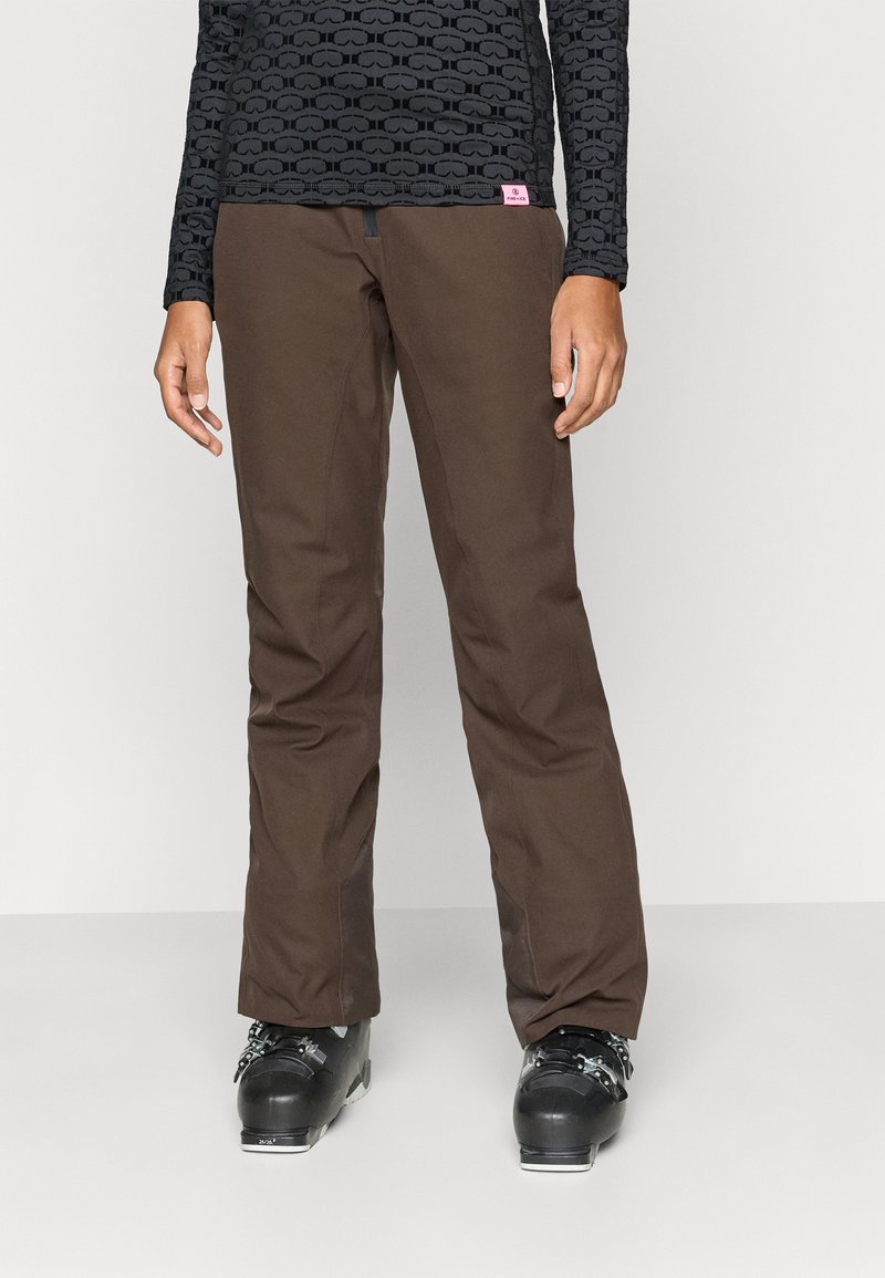 Pruunid suusapüksid vastupidavast materjalist, sirge jala lõikega. Kandestatud roosa brändimärgiga ja mustade suusasaabastega.