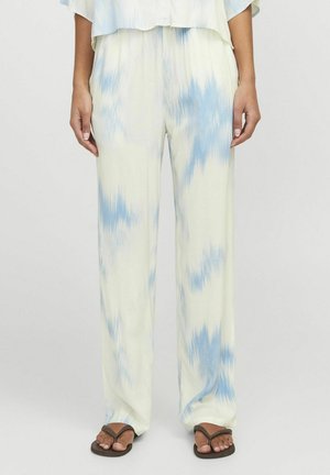 Kerged, kahvatu kollane pükste, millel on sinine tie-dye muster, laiad jalad ja sile tekstuur. Kombineeritud tumedate sussidega.