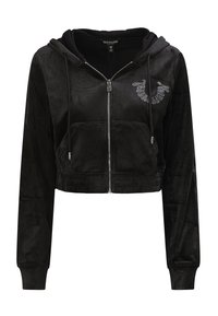 Haut court noir en velours doux, avec des manches longues, une fermeture éclair à l'avant et un logo en rhinestones sur la poitrine gauche. Deux poches avant.