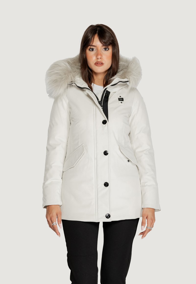 Giacca parka bianca con cappuccio in pelliccia sintetica, dotata di chiusura con zip e bottoni, tasche laterali e dettagli neri a contrasto sulla zip.
