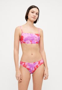 Kwiatowy dwuczęściowy bikini z kwadratowym dekoltem, ozdobiony różowymi i czerwonymi wzorami na jasnym tle. Wykonane z gładkiej elastycznej tkaniny.