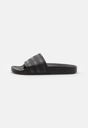 Sort slip-on sandal med tekstureret sål og tre horisontale striber på en bred perforeret rem over foden.