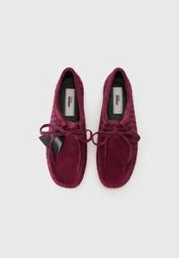 Pantofi burgundii din nabuc, stil mocasin, cu vârful rotund, sistem de închidere cu șireturi și cusături contrastante. Textură netedă cu talpă plată.