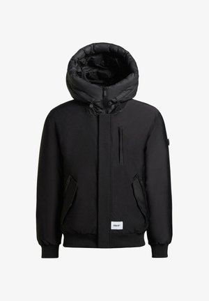 Musta toppatakki, jossa on iso huppu, etuvetoketju, kaksi sivuvetoketjutaskua sekä joustavat hihansuut ja helmassa. Takissa on minimalistinen muotoilu ja logoplässi.