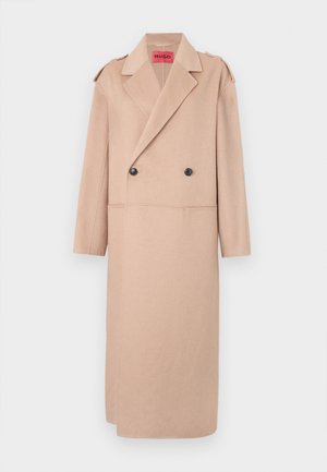 Bež kaput od vune s mješavinom, dvostrukim kopčanjem, velikim reverima i dva prednja džepa. Ima crne dugmadi i detalje na ramenima.