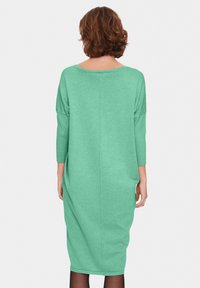 Mintgrön oversized klänning med trekvartslånga ärmar, strukturerad tyg och rak fåll, med en subtil sömdetalj bak.