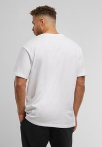 Hvid bomulds t-shirt med korte ærmer, afslappet pasform, rund halsudskæring og en glat tekstur. Simpelt design, ingen synlige mønstre eller accenter.