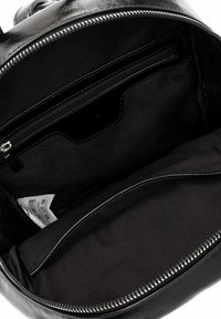 Svart ryggsäck i konstläder med ett innerfack med dragkedja och en slät tygfodring. Öppningen är rund med en silverfärgad dragkedjedetalj.