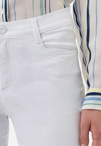 Vita denimjeans med en slät textur, med knappstängning, framfickor och subtila sömdetaljer. Matchas med en randig blus.