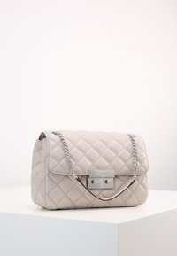 Borsa a tracolla in pelle beige trapuntata con catena argentata e dettaglio della chiusura rettangolare. Forma compatta, superficie liscia e linee pulite.