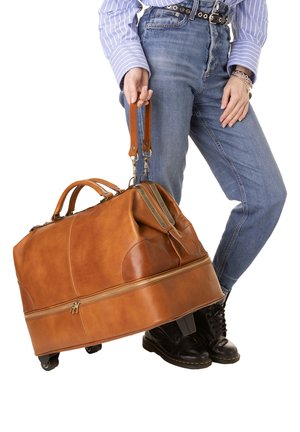 Sac de sport en cuir tan avec un dessus zippé, design rond, poignées robustes et roues à la base. Surface texturée avec des accents cousus.