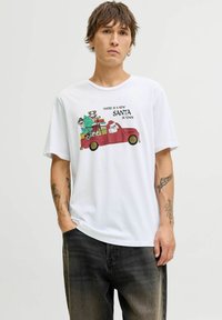 Camiseta blanca de algodón con un gráfico colorido de un camión rojo con Santa, regalos y el texto "HAY UN NUEVO SANTA EN LA CIUDAD."
